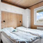 Schlafzimmer mit Bett, weißen Schränken und Holzwand. Fenster zeigt Außenansicht.
