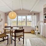 Dining area with table, chairs, and fireplace. Large windows with view outside.