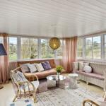 Living room with sofa, chairs, and large windows. View of green areas.