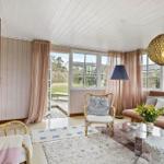 Living room with sofa, chair and large windows. Wooden ceiling and light walls.