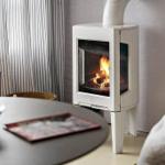 A white wood-burning stove stands next to a round table with chairs.