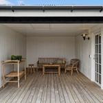 Patio with seating, table, and plants under roof.