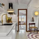Kitchen with countertop, sink, and gold faucet. Passage to living area with chair and rug.