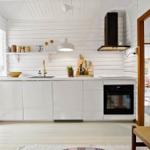 Kitchen with white cabinets, black range hood, and wooden floor.