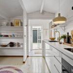 Kitchen with white cabinets, countertop, and shelves. Passage to terrace with doors.