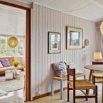 Dining room with round table and chairs. Passage to living room with sofa and window.