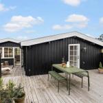 Two black wooden houses with terrace and green table. Background: sky and trees.