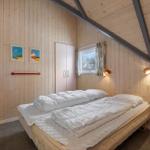 Schlafzimmer mit Bett, Kleiderschrank und Fenster. Holzwände und Deckenbalken.