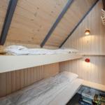 Doppelstockbett in einem Holzraum mit Dachschrägen und Wandlampen.