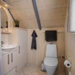 Badezimmer mit Toilette, Waschbecken und Duschvorhang. Holzwände und -decke.