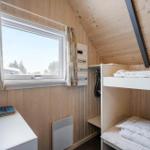 Zimmer mit Doppelstockbett, Fenster und Schreibtisch. Holzwände und Dachschräge.