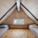 Zwei Betten unter Dachschrägen mit Holzwand und Fenster.