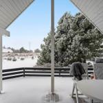 Terrasse mit Tisch und Stühlen, Schnee bedeckt den Boden und Bäume. Blick auf winterliches Landschaft.