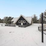 Schwarz gestrichenes Haus mit Schneebedecktem Dach und Gartenzaun im Winter.