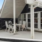 Schnee bedeckt die Terrasse mit Tisch und Stühlen vor einem Haus mit Glasfront.