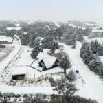 Schneebedeckte Häuser und Bäume in einer ländlichen Umgebung.