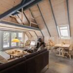 Wohn- und Essbereich mit Holzdecke, Sofa, Esstisch und Fenster zur Terrasse.