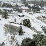 Schneebedeckte Häuser und Bäume in einer ländlichen Umgebung.