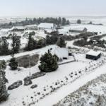 Schneebedeckte Häuser und Bäume in einer ländlichen Umgebung.
