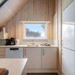 Küche mit Spüle, Kühlschrank und Fenster zum Blick auf Bäume.