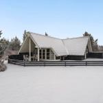 Wohnhaus mit schwarz-weißem Dach und Terrasse im Schnee.
