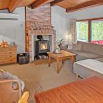 Living room with fireplace, sofa, and wooden furniture. Large windows and TV.