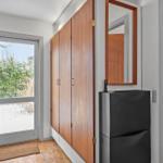 Entrance with wooden floor, cabinet, mirror, and door to outside area.