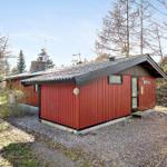 Red wooden house with roof and entrance door in the woods