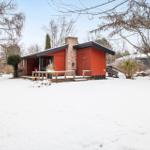 Red house with snow-covered grounds and wooden terrace in winter.