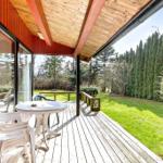 Deck with table and chairs, view of green lawn and trees.