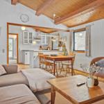 Living room with dining area and kitchen. Wooden ceiling, sofa, dining table, and TV.