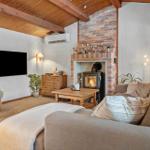 Living room with fireplace, sofa, TV, and wooden ceiling.