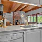 Kitchen with sink, dishwasher, and view into living area with fireplace.