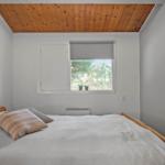 Bedroom with wooden ceiling, bed, and window with roller blind.