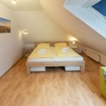 Bedroom with sloped ceiling, bed, sofa, and skylight.