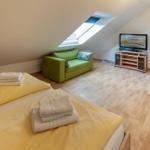 Bedroom with sloped ceiling, green sofa, and TV.