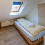 A bedroom with skylight, wooden bed, and wooden floor.