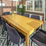Dining room with wooden table, six chairs, and brick wall.