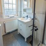 Bathroom with washing machine, sink, and shower.