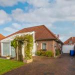 House with garden, terrace, and garage under blue sky.