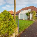 House with terrace and garden. Red roof and paved path.