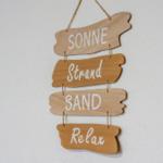 Wooden sign with words Sun, Beach, Sand and Relax on the wall.