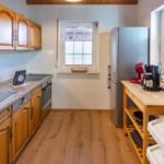 Kitchen with wooden cabinets, sink, refrigerator, and work surface.
