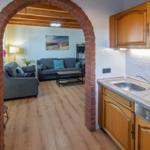 Kitchen with wooden cabinets and view into living room through brick arch.