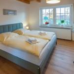 Bedroom with double bed, desk, and window overlooking garden.