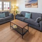 Living room with two gray sofas, wooden floor, and coffee table.