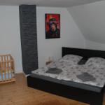 Schlafzimmer mit Babybett, Bett und Wandbild