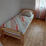 Ein Schlafzimmer mit einem Holzbett, einem Fenster mit Vorhängen und einem Holzboden.