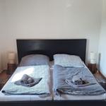 Schlafzimmer mit Doppelbett, Holzdecke und gefliestem Boden. Beide Seiten mit Bettwäsche und Handtüchern.