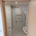 Badezimmer mit Dusche, Waschbecken und Heizkörper an der Wand.